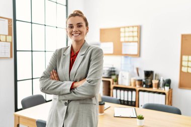 Young woman business worker standing with arms crossed gesture at office