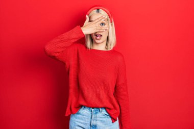 Güzel sarışın kadın, gündelik kırmızı süveter giyer. Şoka girer, yüzünü ve gözlerini kapar. Utanmış bir ifadeyle parmaklarından bakar.. 