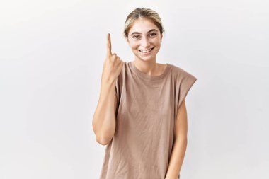 İzole edilmiş arka planda duran genç sarışın kadın başarılı bir fikir işaret ediyor. Heyecanlı ve mutlu. Bir numara.. 