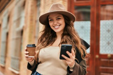 Genç İspanyol turist kadın akıllı telefon kullanıyor ve şehirde kahve içiyor..