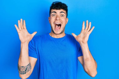 Sıradan mavi tişört giyen genç İspanyol adam çılgınlığı kutluyor ve başarıya hayret ediyor kolları açık ve gözleri açık heyecanla bağırıyor. Kazanan konsept 