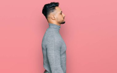 Gündelik giysiler giyen genç bir Arap, rahat bir görünüm takınıyor, kendine güvenen bir gülümsemeyle doğal bir yüz ifadesi sergiliyor.. 