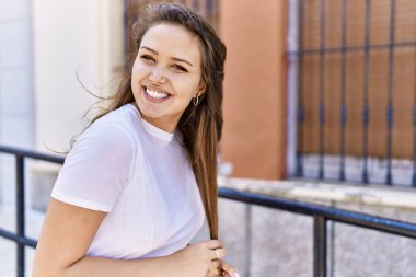 Çekici ve güzel İspanyol kadın güneşli bir havada mutlu gülümsüyor. Güzel esmer kız pozitif gülüşü olan Şehre kendinden emin bakan