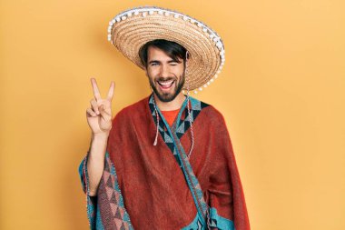 Meksikalı şapkalı genç İspanyol adam kameraya bakıp zafer işareti yaparken gülümsüyor. İki numara.. 