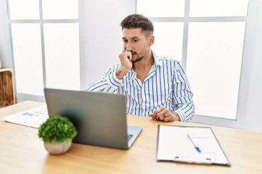 Ofiste çalışan sakallı, bilgisayarlı, stresli ve gergin görünen elleri tırnaklarını yiyen genç ve yakışıklı bir adam. anksiyete. 