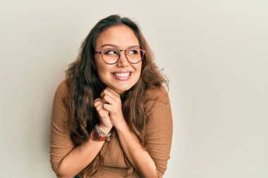 Gündelik kıyafetler ve gözlük takan genç İspanyol kız gergin ve heyecanlı bir şekilde çenesine bakıp yan tarafa bakıyor. 