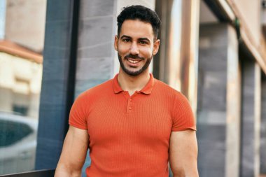 Genç İspanyol adam gülümseyerek şehirde mutlu mesut dikiliyor..