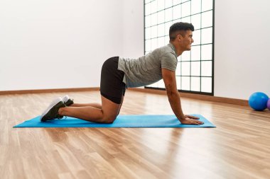 Genç İspanyol adam gülümsüyor spor merkezinde esniyor.