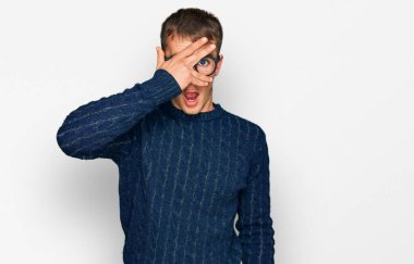 Gündelik kıyafetler giyen ve gözlük takan genç sarışın adam şok içinde yüzünü ve gözlerini kapayarak utangaç ifadesiyle parmaklarından bakıyor.. 