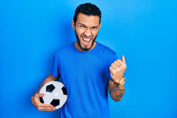 髭を生やしたヒスパニック系の男は怒ってサッカーボールを保持し 怒りを叫びながら拳をフラストレーションと激怒を上げる 怒りと攻撃的な考え方 — ストック写真