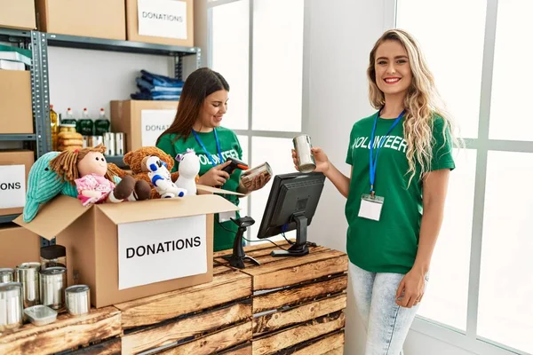 İki gönüllü kadın, hayır kurumunda çalışmaktan mutlu gülümsüyor..