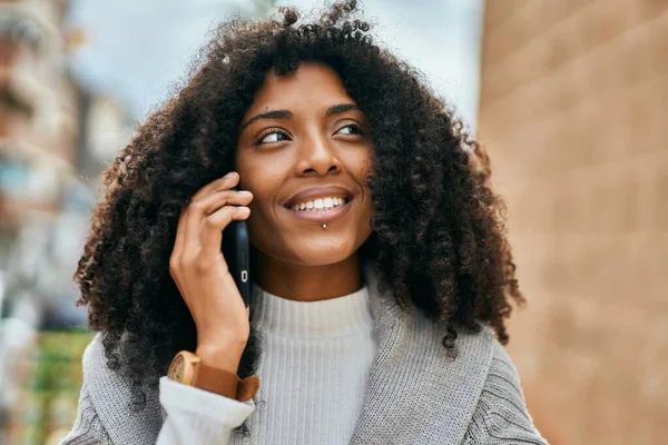 若いアフリカ系アメリカ人女性が笑顔で市内のスマートフォンで話しています — ストック写真
