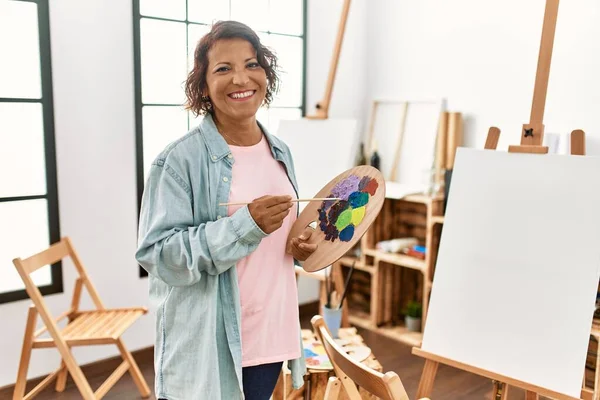 Orta yaşlı İspanyol ressam gülümsüyor. Resim stüdyosunda mutlu çizimler..