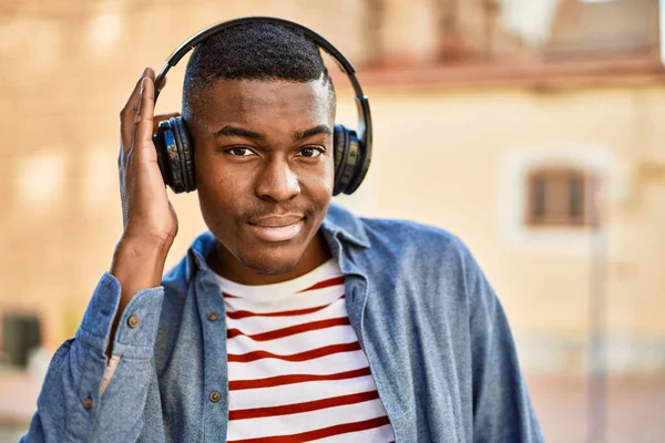 Młody Afrykanin Uśmiecha Się Szczęśliwy Używając Słuchawek Mieście — Zdjęcie stockowe