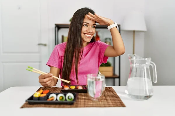 若いブルネットの女性は箸を使って寿司を食べる非常に幸せと笑顔遠くに手を頭の上に見ている 検索の概念 — ストック写真