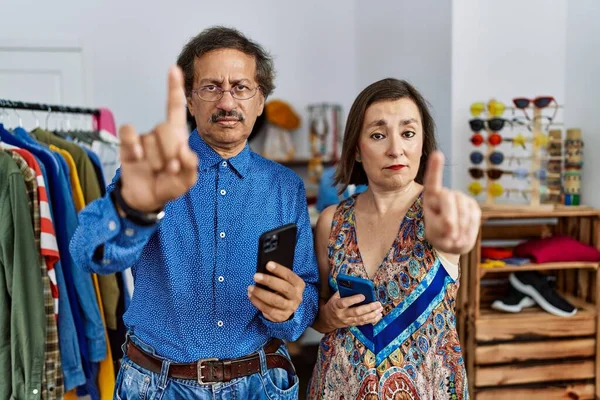 中世異人種間のカップルで小売店で使用スマートフォンを指差す指と怒りの表現 ジェスチャーを示さない — ストック写真
