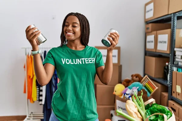 身穿志愿制服的年轻非洲裔美国妇女拿着罐头食品在慈善中心 — 图库照片
