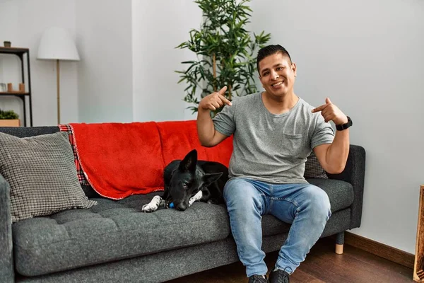 Jovem Latino Homem Cão Sentado Sofá Casa Olhando Confiante Com — Fotografia de Stock