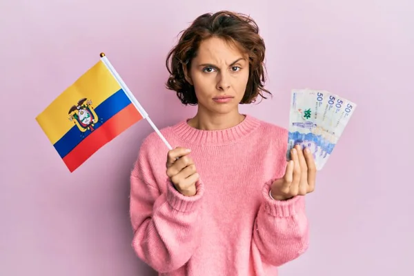 コロンビアの国旗とコロンビアペソ紙幣を持っている若いブルネットの女性は懐疑的で緊張し 問題のために動揺して眉をひそめている 否定的な人 — ストック写真