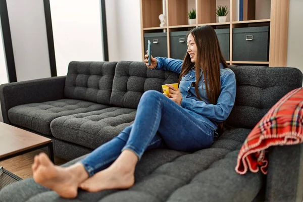 Jovem Chinesa Bebendo Café Usando Smartphone Sentado Sofá Casa — Fotografia de Stock