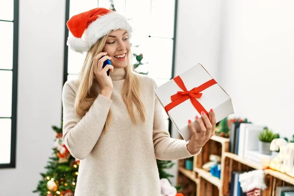 Young Blonde Woman Talking Smartphone Holding Christmas Gift Home — Φωτογραφία Αρχείου