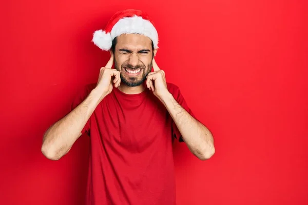 Молодий Іспаномовний Чоловік Різдвяній Шапці Покриває Вуха Пальцями Роздратованим Виразом — стокове фото