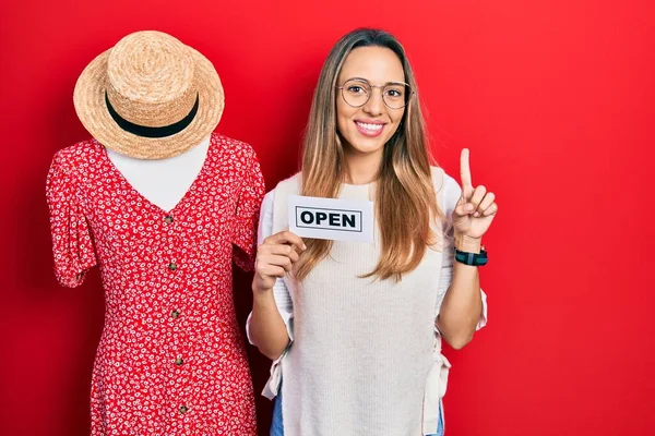 幸せな顔でアイデアや質問を指差す指で笑顔でオープンショッピングビジネスバナーを保持美しいヒスパニック女性 ナンバーワン — ストック写真