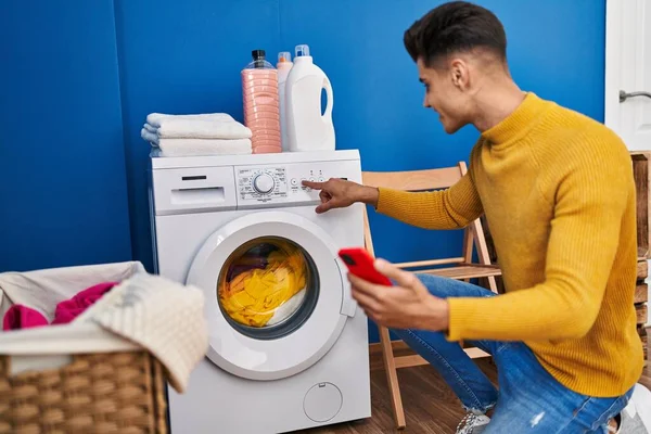 在洗衣店用智能手机洗衣服的年轻人 — 图库照片