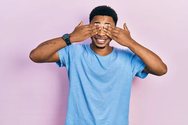陽気で面白い手で目を覆うカジュアルなブルーのTシャツを着た若いアフリカ系アメリカ人男性 視覚障害の概念 — ストック写真