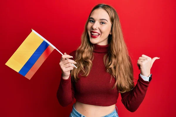 Joven Rubia Sosteniendo Bandera Colombia Apuntando Con Pulgar Hacia Lado —  Fotos de Stock