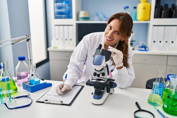 Giovane Donna Latina Uniforme Scienziato Con Scrittura Microscopica Sugli Appunti — Foto Stock