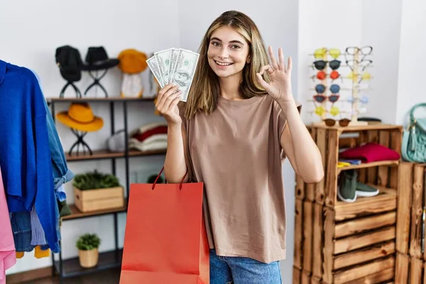 Νεαρή Ξανθιά Γυναίκα Κρατώντας Τσάντες Ψώνια Και Δολάριο Στο Κατάστημα — Φωτογραφία Αρχείου