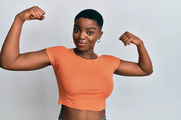 Mujer Afroamericana Joven Con Camiseta Naranja Casual Mostrando Los Músculos —  Fotos de Stock