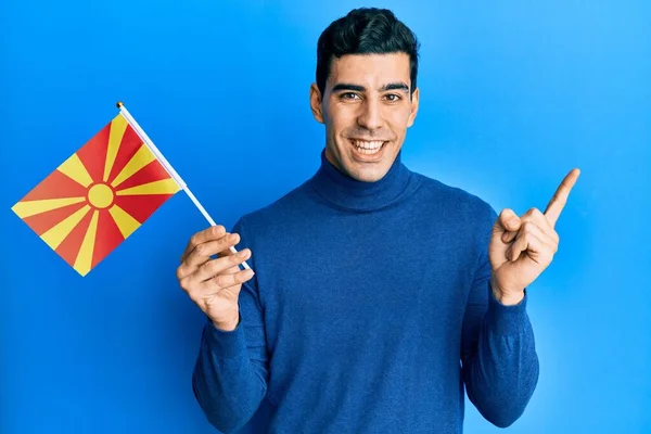 Όμορφος Ισπανός Κρατώντας Μακεδονική Σημαία Χαμογελώντας Χαρούμενος Δείχνοντας Χέρι Και — Φωτογραφία Αρχείου