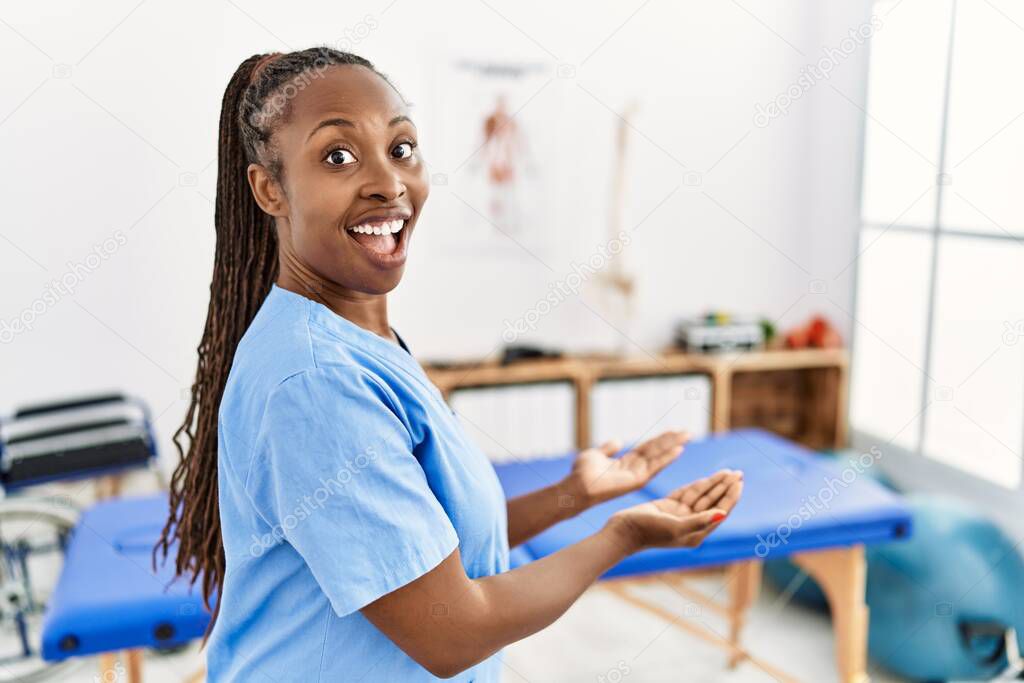 Black woman with braids working at pain recovery clinic pointing aside with hands open palms showing copy space, presenting advertisement smiling excited happy 