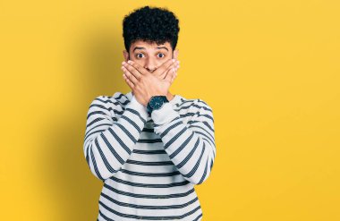 Sıradan çizgili süveter giyen sakallı genç bir Arap yanlışlıkla elleriyle ağzını kapatmış. gizli kavram. 