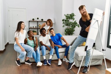 Bir grup genç arkadaş gülümseyerek evde çizim oyunu oynuyorlar..