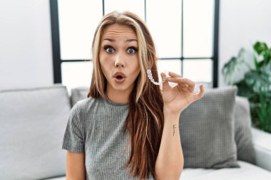 Kafkasyalı genç bir kadın görünmez bir hizacı tutuyor. Korktu ve şaşkınlık içinde ağzı açık kaldı. İnançsız yüz. 