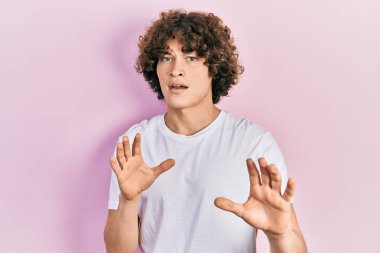 Yakışıklı beyaz tişört giyen, korku ifadesinden korkan ve dehşete düşmüş genç adam. El hareketlerini bırak, şok içinde bağır. panik konsepti. 