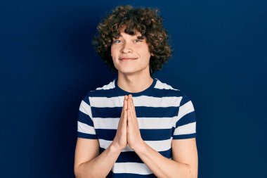 Yakışıklı, çizgili tişört giyen, elleri birarada dua eden, affedilmek isteyen, kendinden emin gülümseyen genç adam.. 