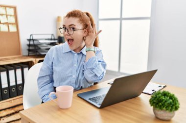 Ofiste çalışan genç, kızıl saçlı bir kadın. Kulaktan kulağa gülümseyen bir bilgisayarla dedikoduları ve dedikoduları dinliyor. Sağırlık kavramı. 