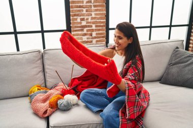 Genç İspanyol kadın gülümsüyor. Elinde ev yapımı bir eşarp tutuyor.