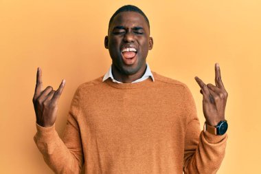 Sıradan kıyafetler giymiş, çılgın bir ifadeyle bağıran, elleri havada rock sembolü yapan genç bir Afrikalı Amerikalı. Müzik yıldızı. ağır kavram. 