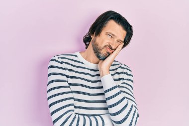 Orta yaşlı, günlük kıyafetler giyen, yorgun görünen ve depresyondan sıkılmış kollarını kavuşturan beyaz bir adam.. 