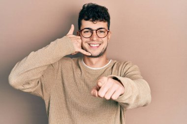 Günlük kıyafetler ve gözlük takan genç İspanyol adam gülümsüyor telefonda konuşuyor ve seni işaret ediyor. Ara beni.. 