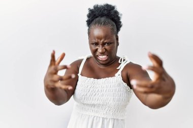 Genç Afrikalı bir kadın izole edilmiş beyaz arka planda duruyor öfkeyle bağırıyor, elleri boğmaya çalışıyor, deli gibi bağırıyor. 