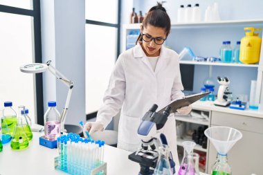 Laboratuvarda çalışan, bilim adamı üniforması giyen genç İspanyol kadın.