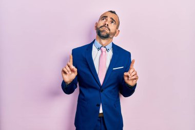 Genç İspanyol takım elbiseli ve kravatlı adam üzgün ve üzgün görünüyor, parmaklarıyla yönü gösteriyor, mutsuz ve depresif.. 