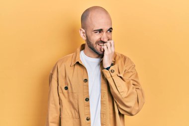 Günlük kıyafetler giyen genç kel adam gergin ve gergin görünüyor. Ağzı tırnak yiyen eller. anksiyete. 