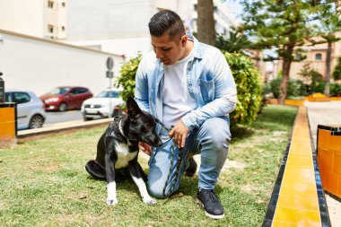 Genç latin adam gülümseyerek şehirde köpekle dikilmekten mutlu..